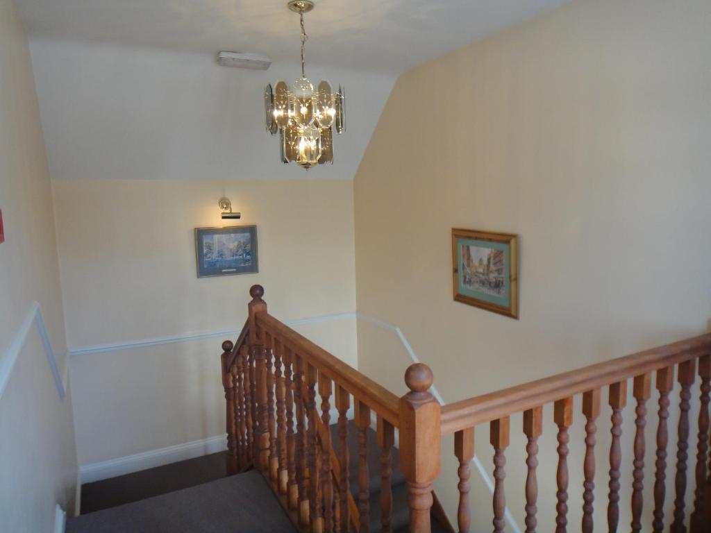 a hallway with a staircase with a chandelier at Gibtel Lodge & Cafe in Slough