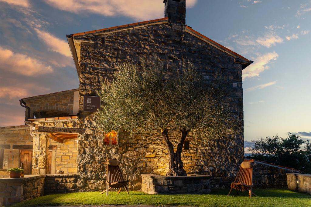 ein Steingebäude mit zwei Stühlen vor einem Baum in der Unterkunft Wine House Rakar in Gračišče