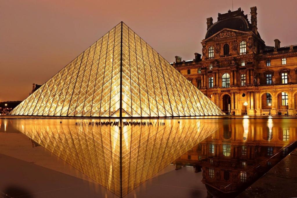 una imagen de la pirámide del Louvre frente a un edificio en Havre de paix à 15’ Paris et 10’ Stade de France en Saint-Denis