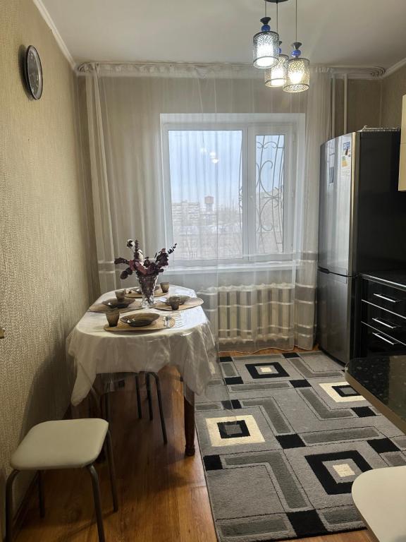 una pequeña cocina con mesa y nevera en Двухкомнатная квартира в центре, en Semey