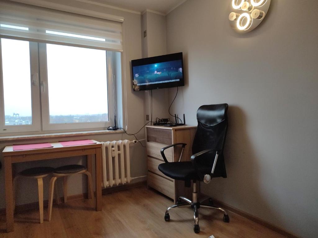 um quarto com uma secretária, uma televisão e uma cadeira em garsoniera em Gdansk