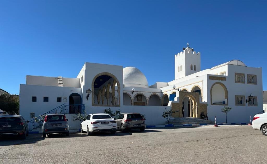 una chiesa bianca con auto parcheggiate in un parcheggio di Dar Yessine Boutique Hôtel a Sousse