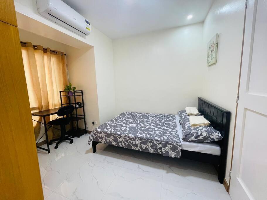 um pequeno quarto com uma cama e uma secretária em A relaxing and accessible condominium unit. em Manila