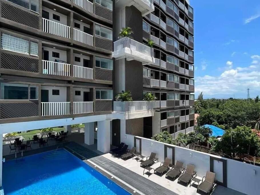 伊洛伊洛的住宿－WV2 Condotel Luxury，公寓大楼设有游泳池和椅子