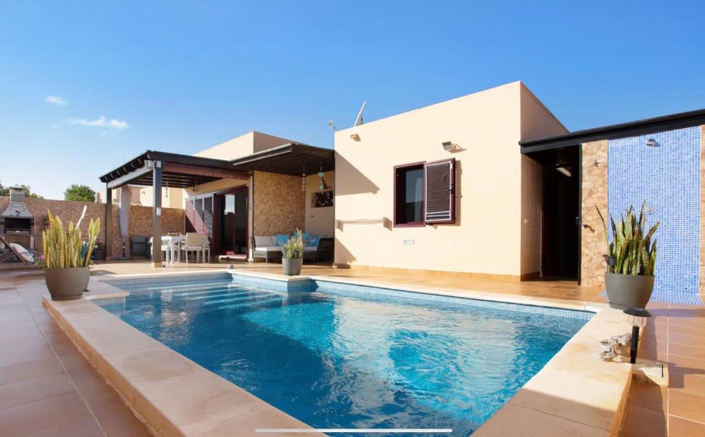 a swimming pool in front of a house at Villa Amistad in La Oliva