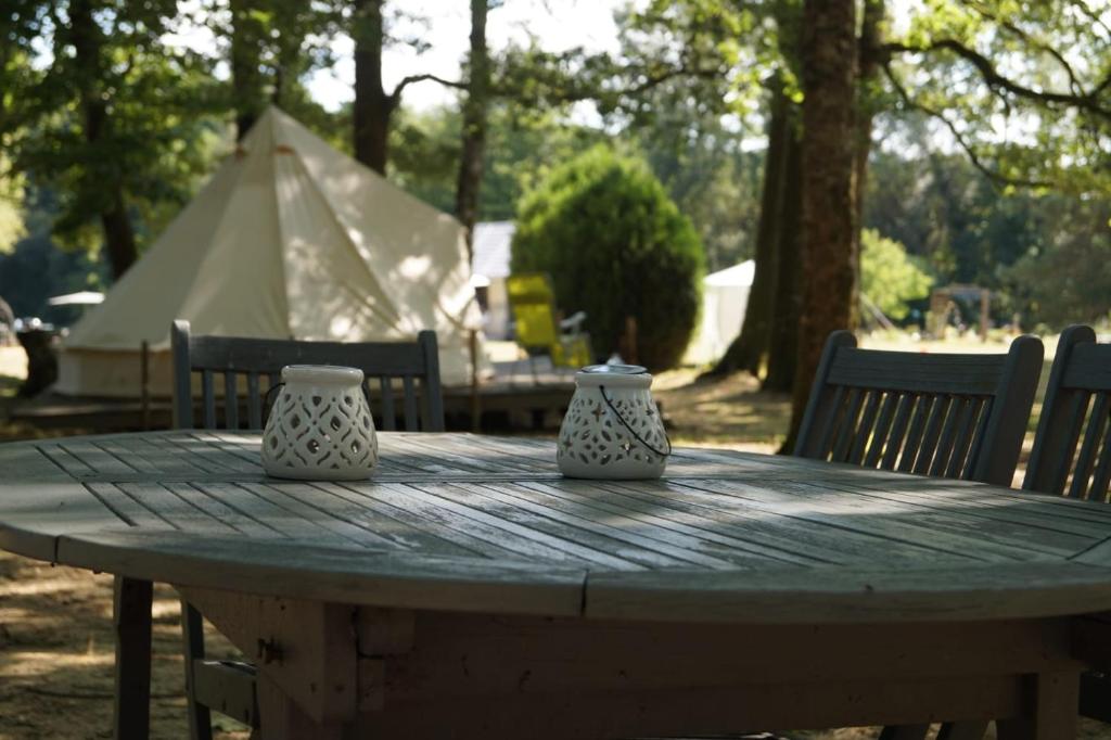 una mesa de madera con dos jarrones encima en Camping sous les belles etoiles, en Peyrilhac