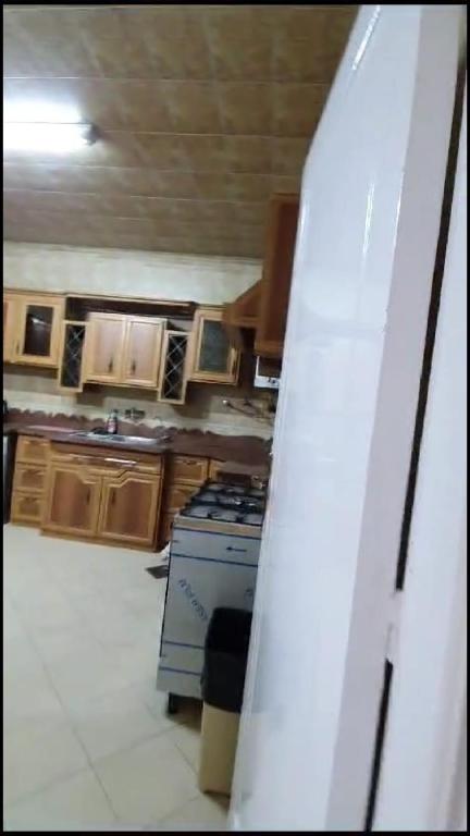 een keuken met een fornuis en houten kasten bij شقة مفروشة فاخرة بأرقى مواقع المنصورة in Mît Khamîs