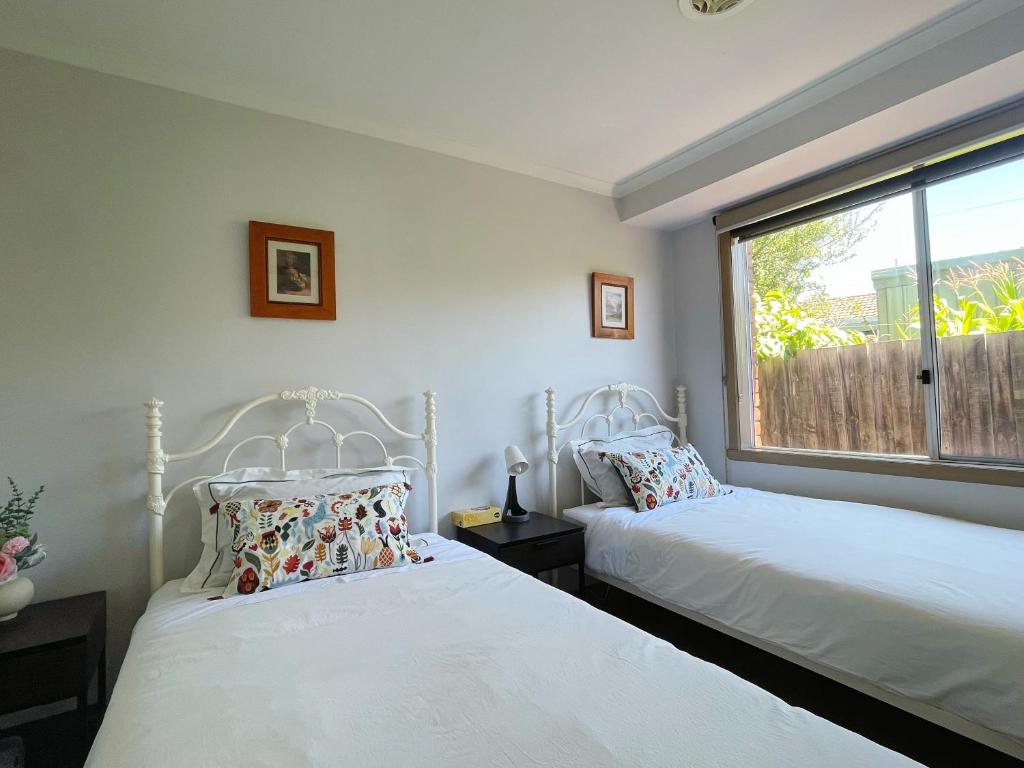 2 camas en una habitación con ventana en YF Hostel, en Craigieburn