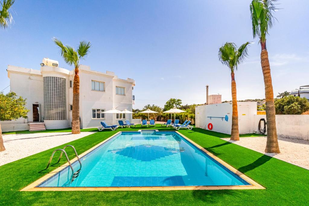 une piscine avec des palmiers en face d'une maison dans l'établissement Varvara's Villa, à Ayia Napa