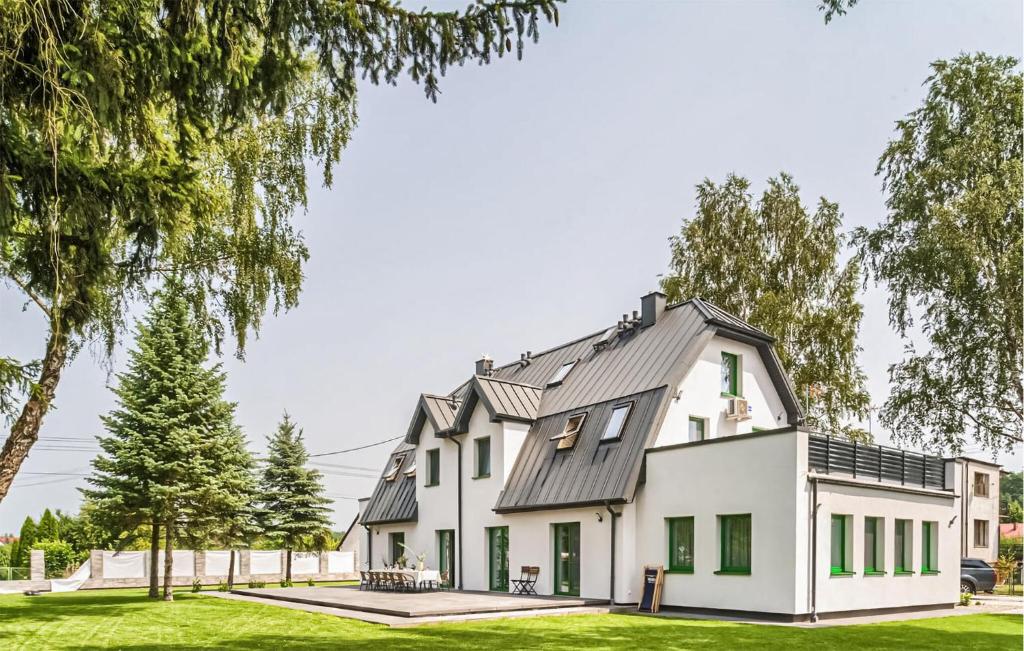 a white house with a gray roof and green windows at Cozy Apartment In Tlen With Kitchen in Tleń