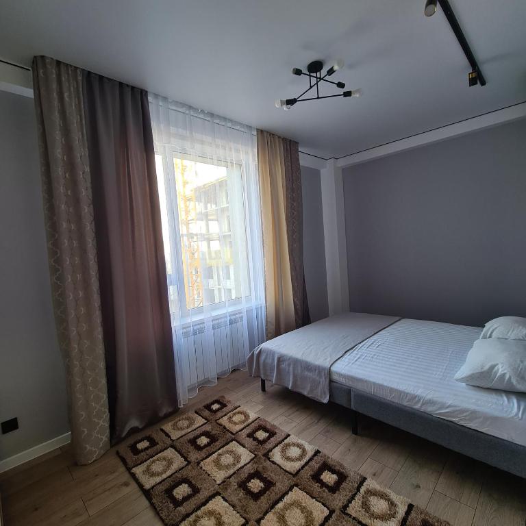 a bedroom with a bed and a large window at Квартира in Shymkent