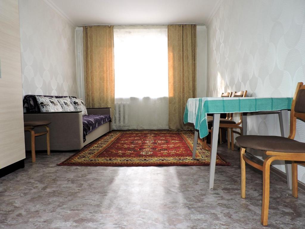 a living room with a table and a window at NBG Flat in Almaty