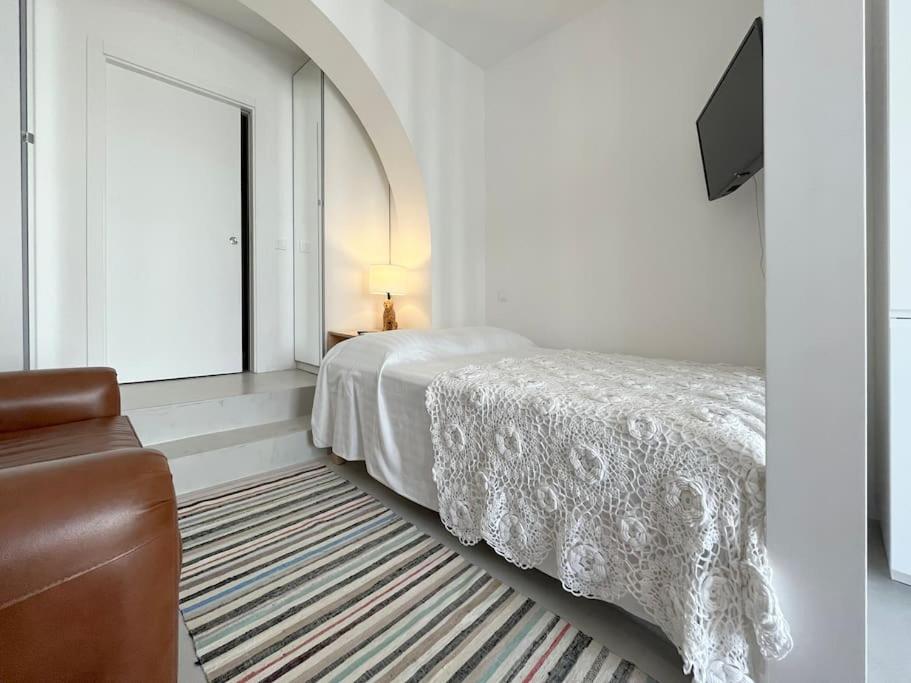 a bedroom with a bed and a couch and a window at Casa Alta T0 in Castelo de Vide