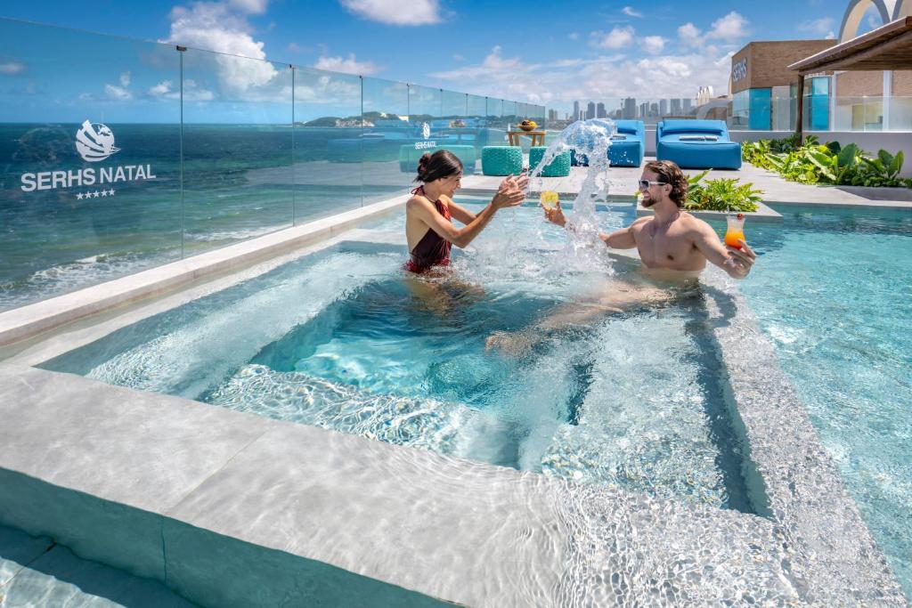 dos personas jugando en el agua en una piscina en SERHS Experience Suítes, en Natal