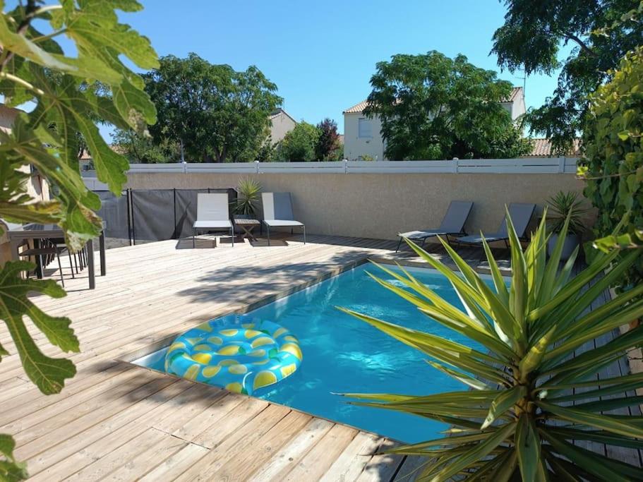 einen Hinterhof mit einem Pool und einer Holzterrasse in der Unterkunft Villa aiguës marines in Pérols