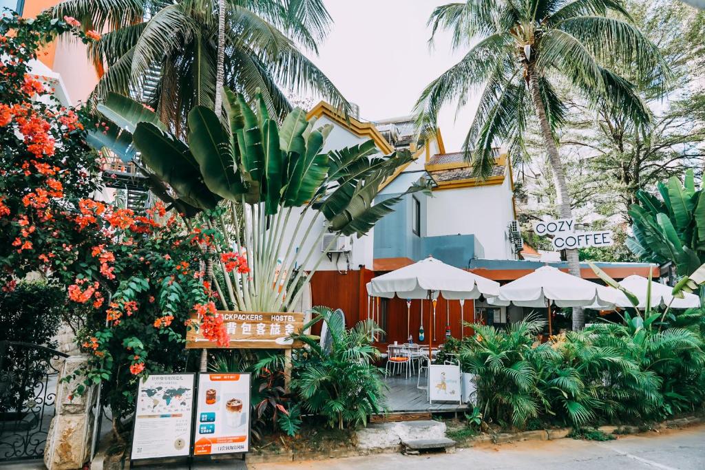 a garden in front of a building with palm trees at Sanya IPK BACKPACKERS HOSTEL in Sanya