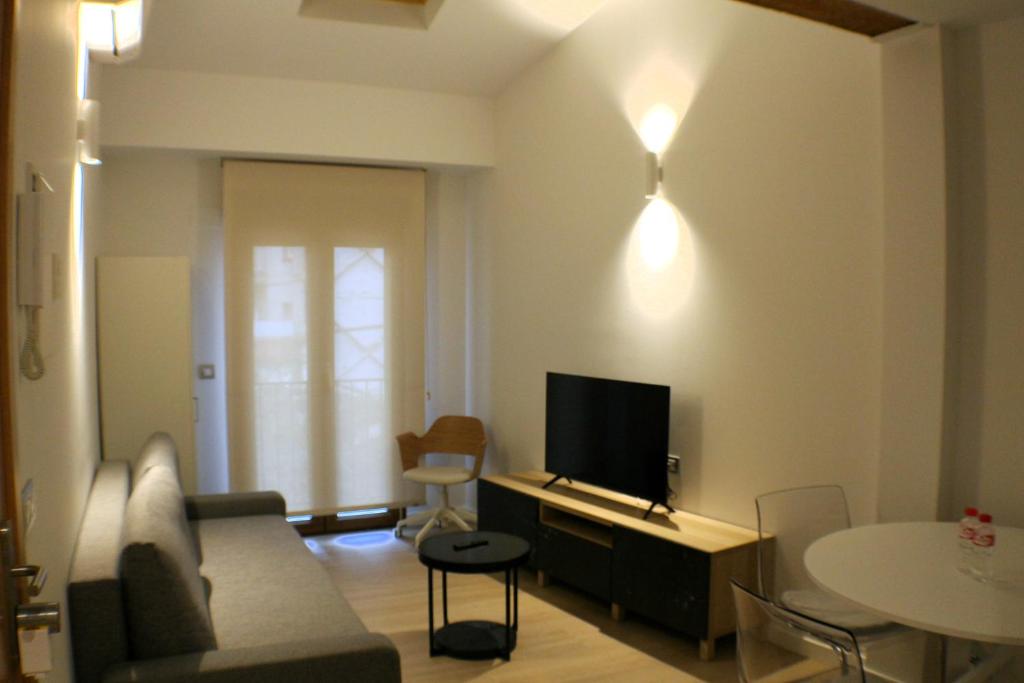 a living room with a couch and a tv and a table at APARTAMENTOS PICOS DE EUROPA in Santander