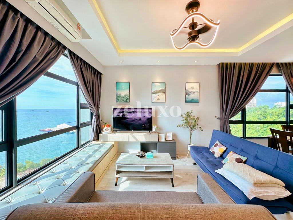 uma sala de estar com um sofá azul e janelas grandes em #11 Jesselton Quay City Pads Seaview Corner em Kota Kinabalu