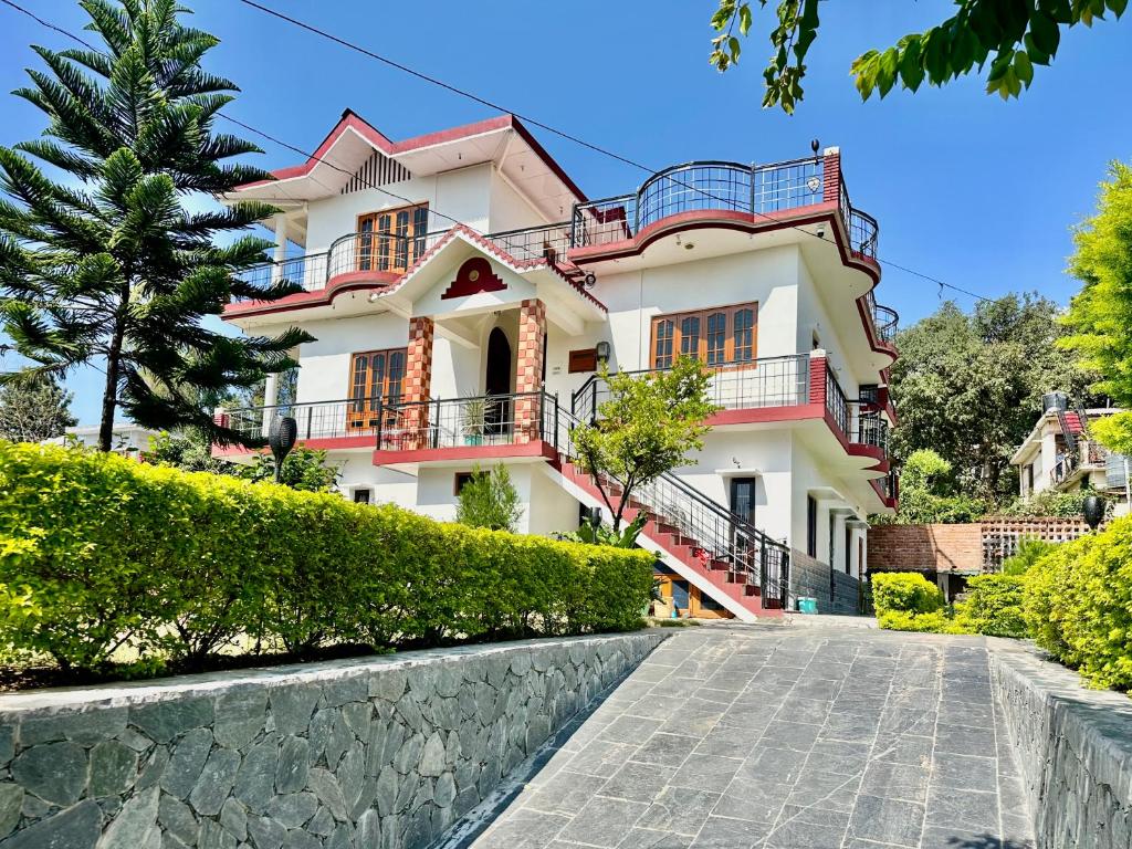 een groot wit huis met rode balkons in een straat bij Snow Biscuit Villa in Dharamshala