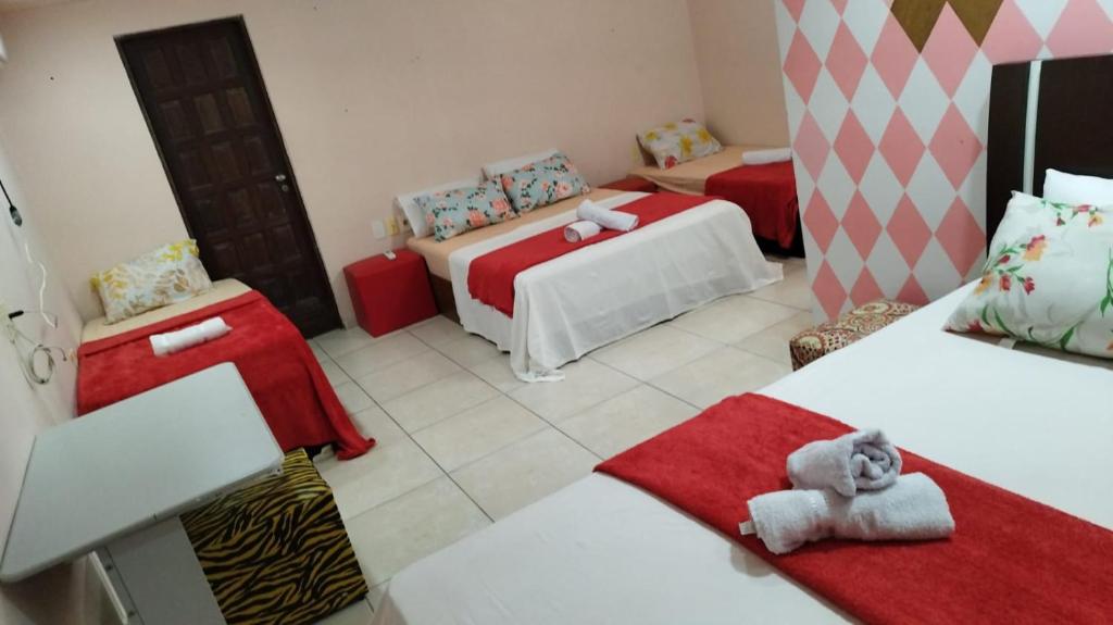 a room with two beds with red and white sheets at HOSTEL, POUSADA e APART em PORTO SEGURRO PRAIA in Porto Seguro
