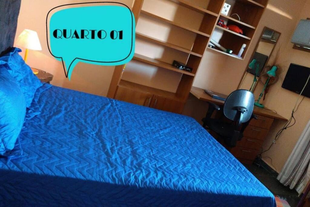 een slaapkamer met een bed met een blauw dekbed en een spreekbubbel bij Casa Temporada à Beira da Praia in Maricá
