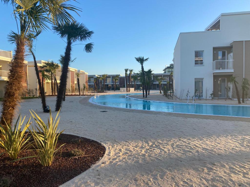 um resort com piscina, palmeiras e edifícios em Romantika apartment em Lido di Jesolo