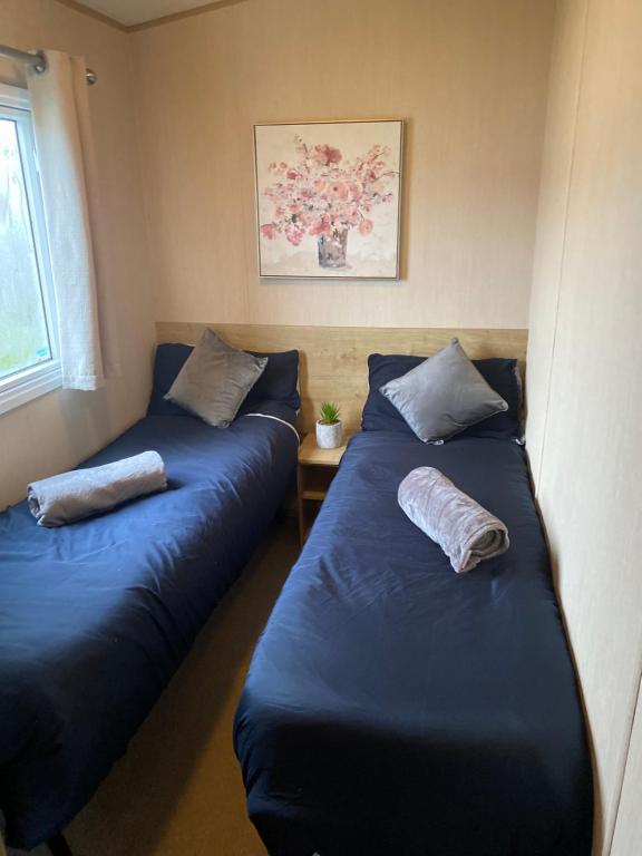 Duas camas num quarto com lençóis e almofadas azuis em Lancaster Crescent Hot Tub Hideaway em Tattershall