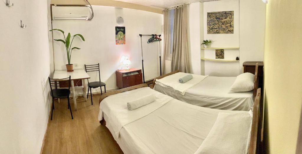 a hotel room with two beds and a table and a desk at Hello Fox GuestHouse in Tbilisi City