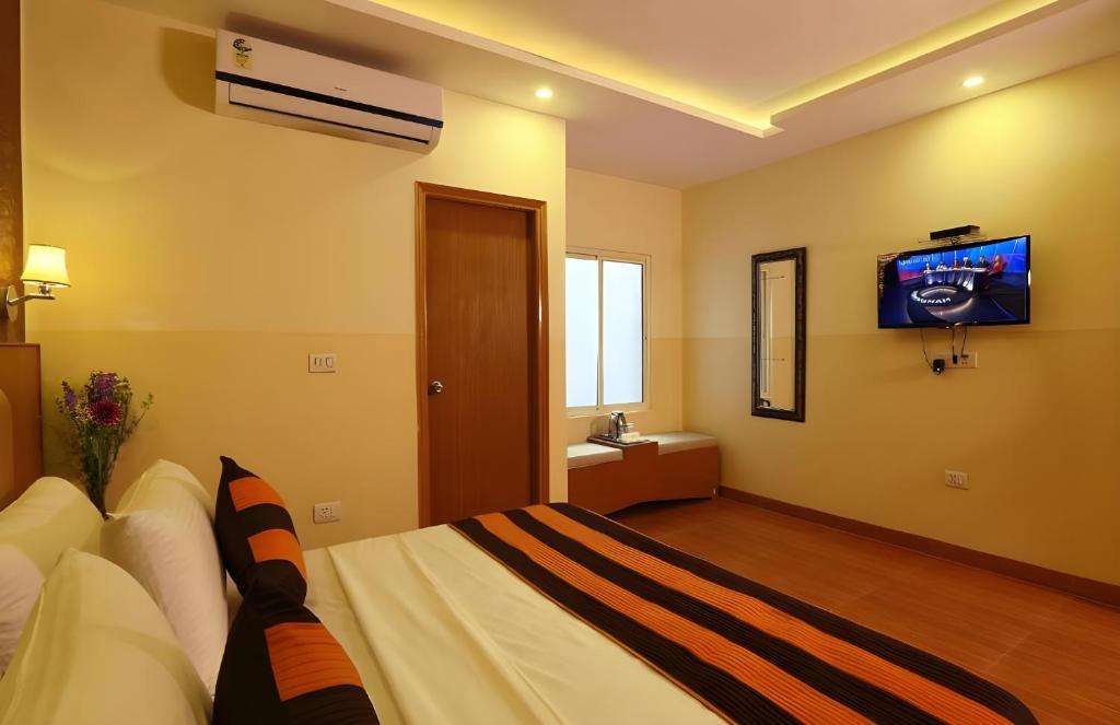 Hotel Aeroporto Near By Delhi International Airport في نيودلهي: غرفة نوم مع سرير وتلفزيون على الحائط