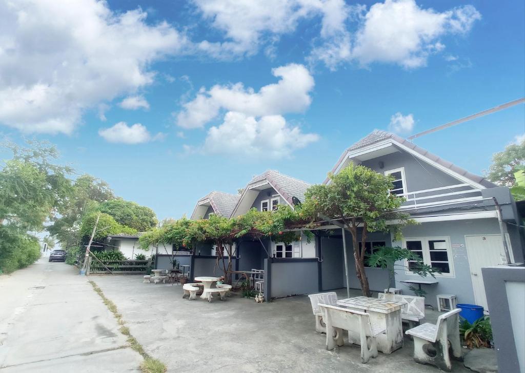 une maison avec une table et des bancs devant elle dans l'établissement บ้านพักมาซามิโฮม หาดเจ้าสำราญ Mazami Homes At Chao Samran Beach Phetchaburi, à Ban Hat Cha Samran