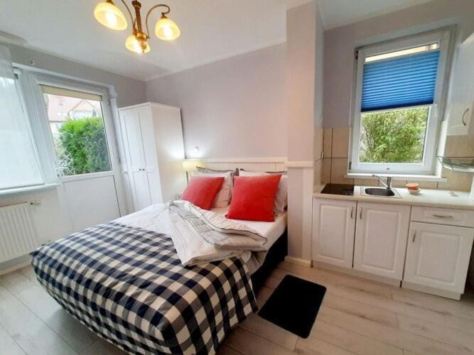 Schlafzimmer mit einem Bett mit roten Kissen und einem Waschbecken in der Unterkunft Apartment for 2 people in Mi dzyzdroje in Misdroy