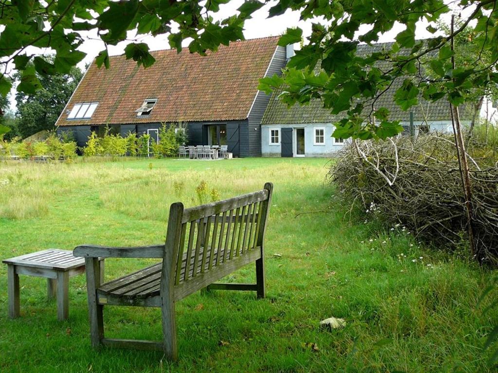 a park bench sitting in the grass in front of a house at Gasterij Landschot in Hoogeloon