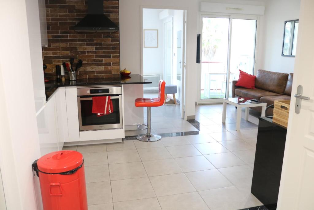 - une cuisine et un salon avec un tabouret rouge dans l'établissement T2 moderne, vintage & cosy, à Sète