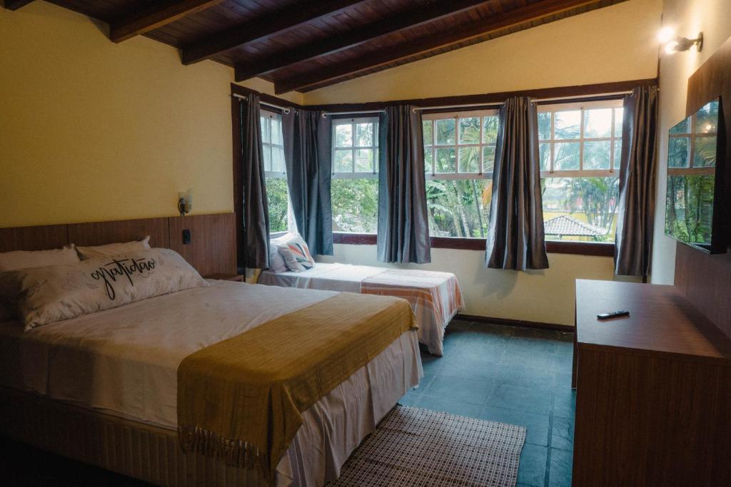 a hotel room with two beds and windows at Pousada Serra da Bocaina Paraty in Paraty
