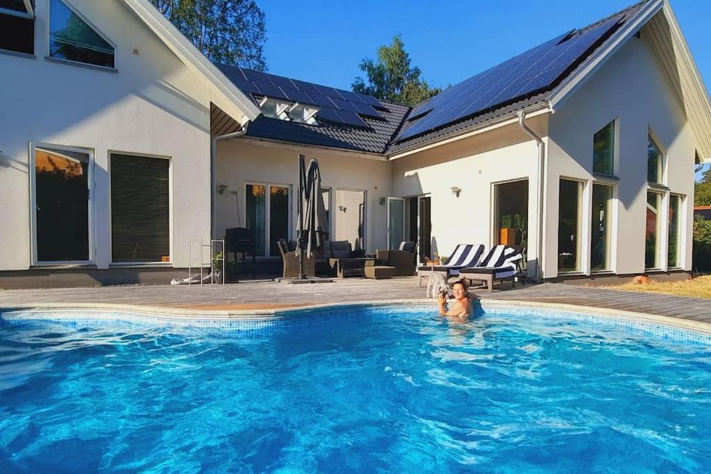 een man in een zwembad naast een huis bij Exklusive villa on the coast close to Stockholm in Åkersberga