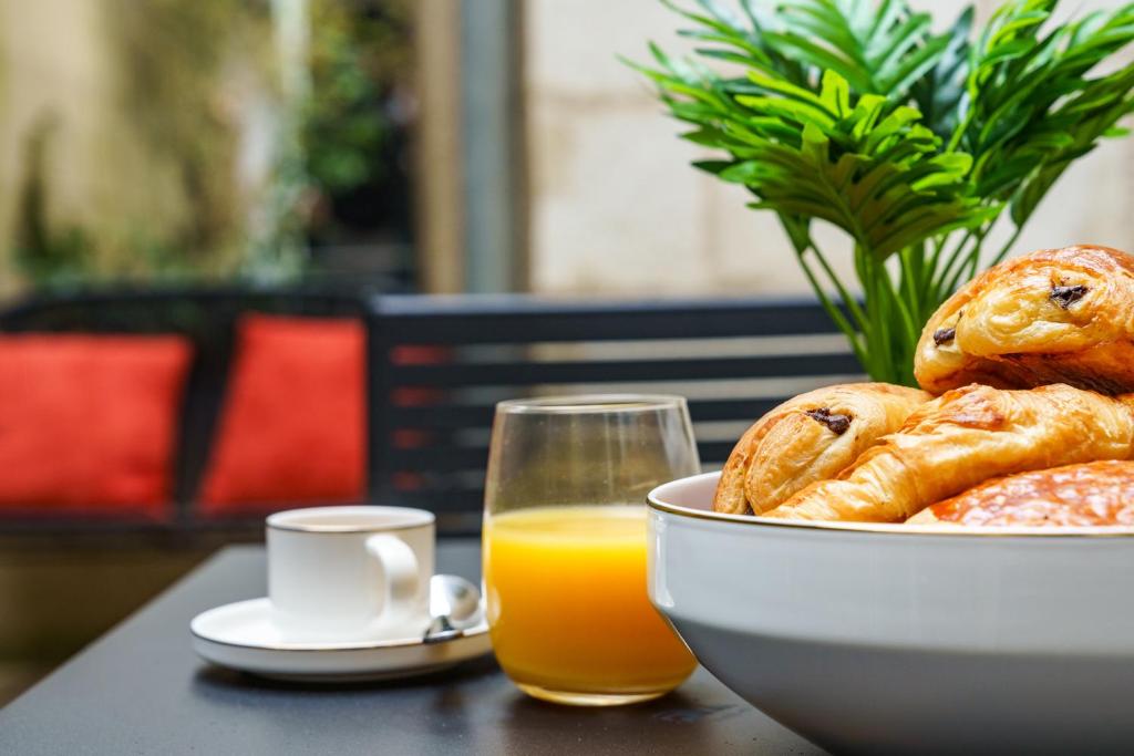 a bowl of bread and a glass of orange juice at La Cour de l'Opera - PrestiPlace Tours in Tours