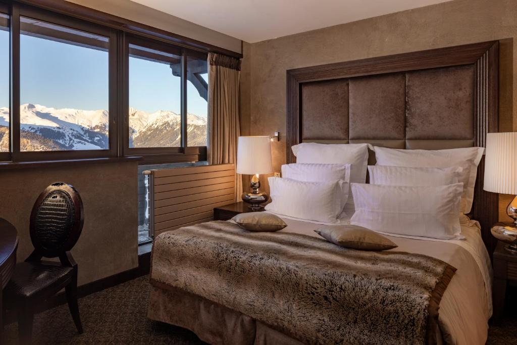 - une chambre avec un grand lit et une vue sur la montagne dans l'établissement Le Lana, à Courchevel