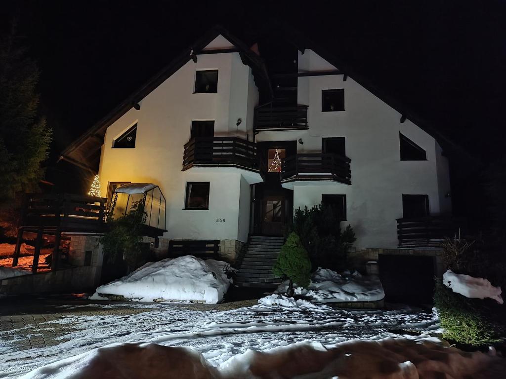 ein großes weißes Gebäude mit Schnee in der Nacht in der Unterkunft Apartmány Nový Svět 548 in Harrachov