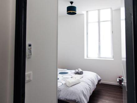 a white room with a bed with a window at Belle Isle in Châteauroux