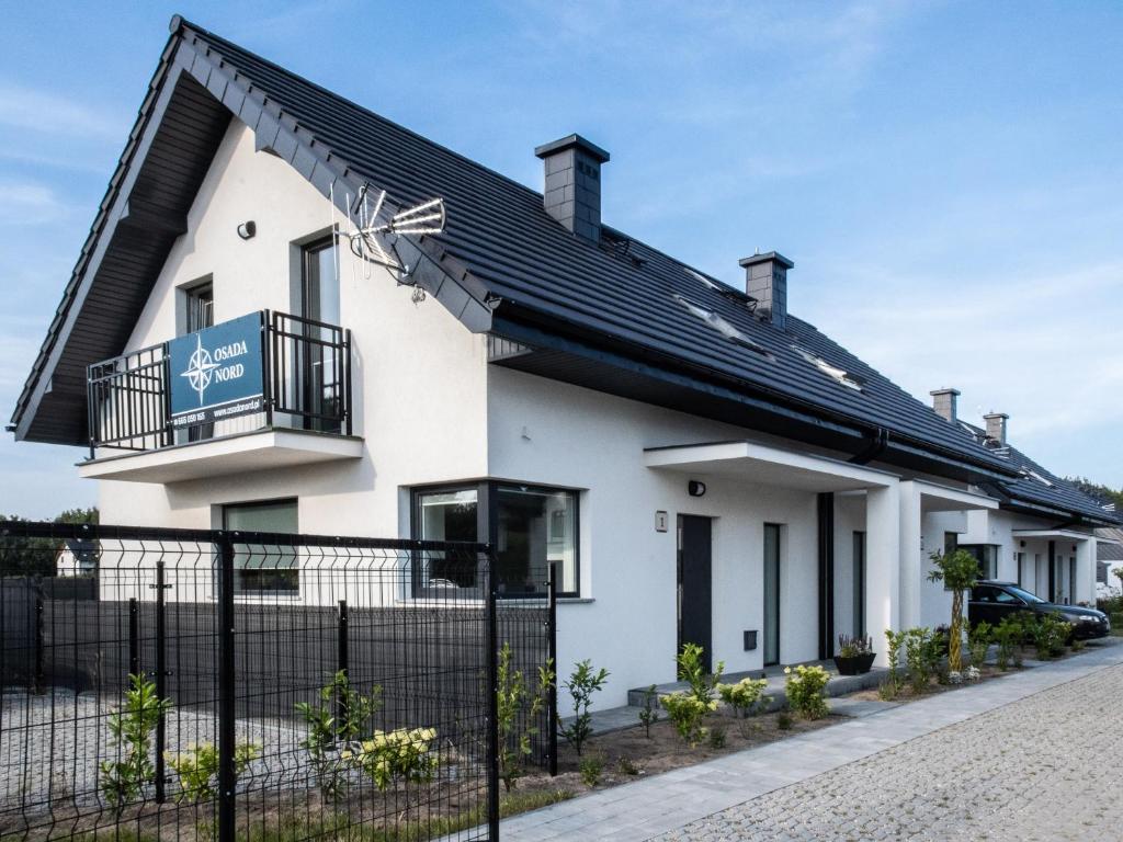 a white house with a black roof at Osada Nord domki wypoczynkowe in Jastrzębia Góra