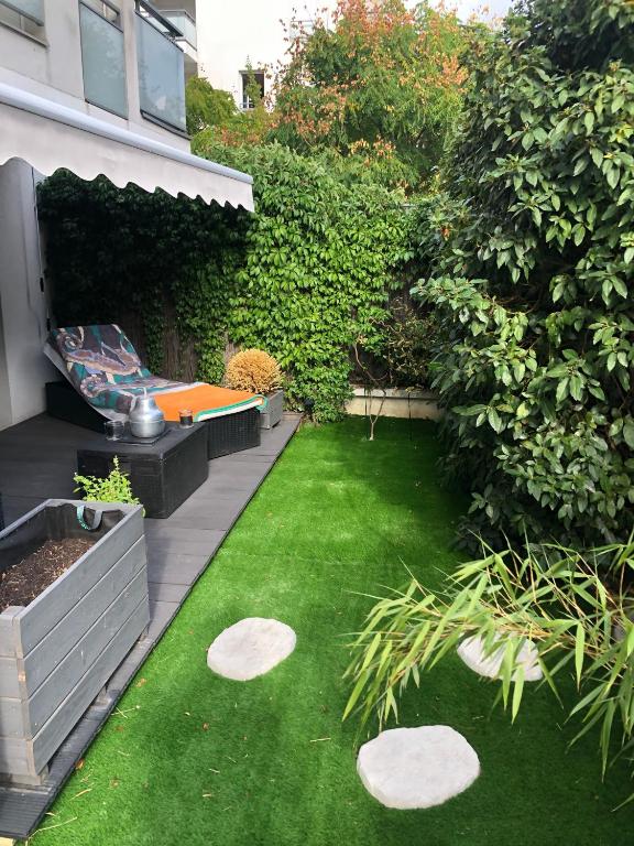 une cour arrière avec un jardin avec un banc et de l'herbe dans l'établissement Appartement avec Jardin - La Plaine Saint Denis, à Saint-Denis