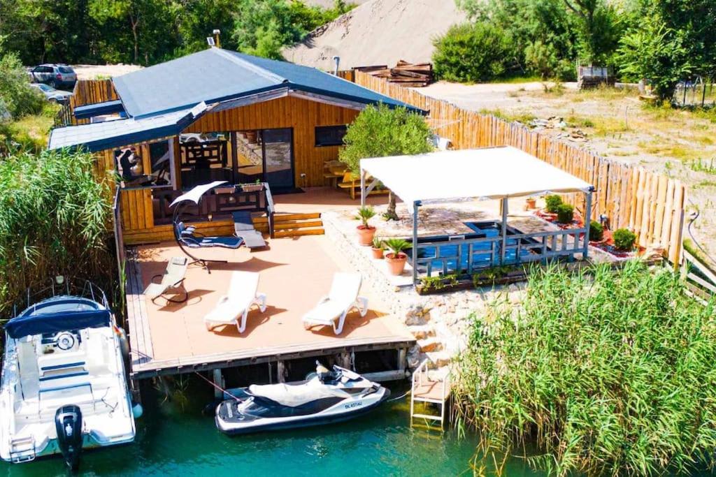 uma casa com um barco numa doca na água em Jack und Benny Insel Bojana em Sveti Nikola