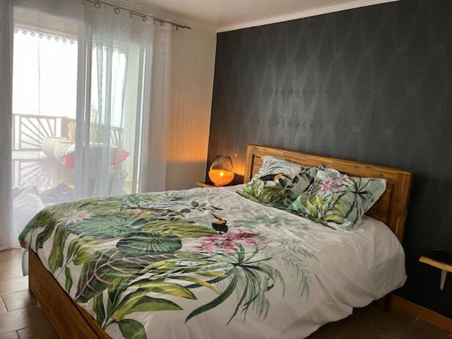 1 dormitorio con 1 cama con colcha de flores en Les panoramiks des Makes, en Saint-Louis