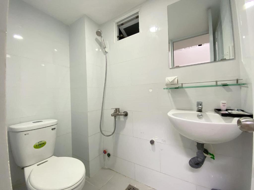 a white bathroom with a toilet and a sink at Khách Sạn An Chi in Ho Chi Minh City