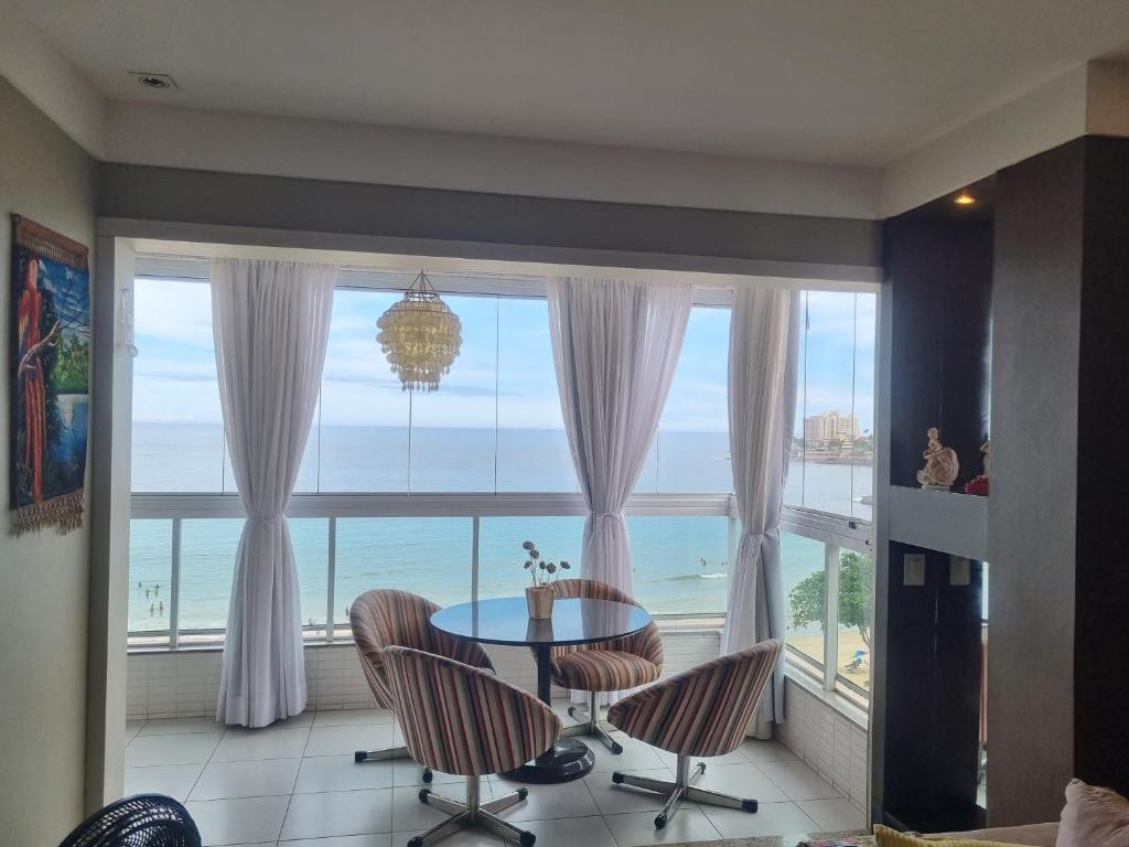 uma sala de jantar com vista para o oceano em Apartamento FRENTE PARA 0 MAR - PÉ NA AREIA - 3 SUITES COM AR CONDICIONADO, 2- VAGAS DE GARAGEM - FINAMENTE DECORADO - PRAIA DO MORRO-INTERNET -WI-FI -TV COM SERVIÇOS DE DISNEY PLUS - NETFLIX -HBO MAX -STAR MAX - JOGOS AMAZON FIRE STICK - ALEXIA em Guarapari