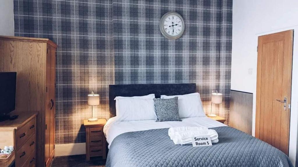 ein Schlafzimmer mit einem Bett mit einer Uhr an der Wand in der Unterkunft Croyland Guest House in Tenby