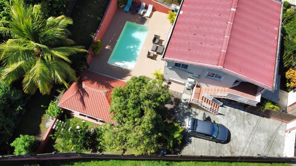 Cette chambre offre une vue sur une maison dotée d'un toit rouge et d'une piscine. dans l'établissement Résidence Belle Anse Trois-ilets, à Les Trois-Îlets