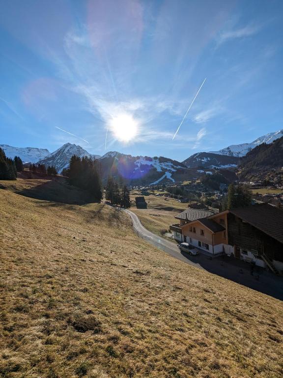 - une vue sur un champ avec une maison et des montagnes dans l'établissement Zimmer in Adelboden, à Adelboden