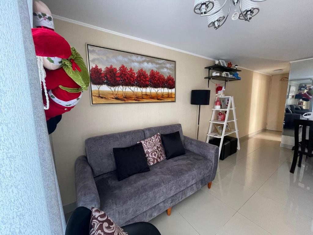un soggiorno con divano grigio e un dipinto di alberi rossi di Lindo y Acogedor Departamento en Lima! a Lima