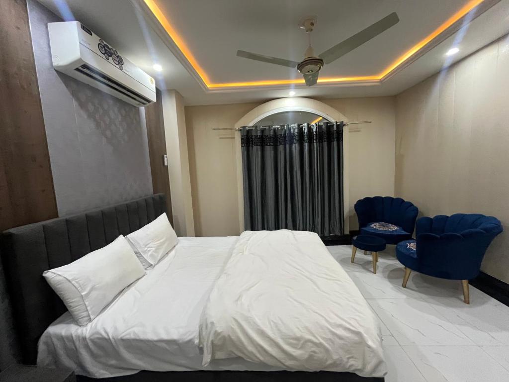 Khāriān的住宿－Kharian-Inn Hotel，一间卧室配有白色的床和2把蓝色的椅子